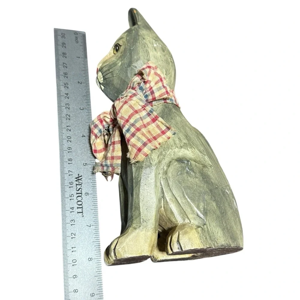 hand-carved wooden cat figurine with a painted finish and a plaid cloth scarf.